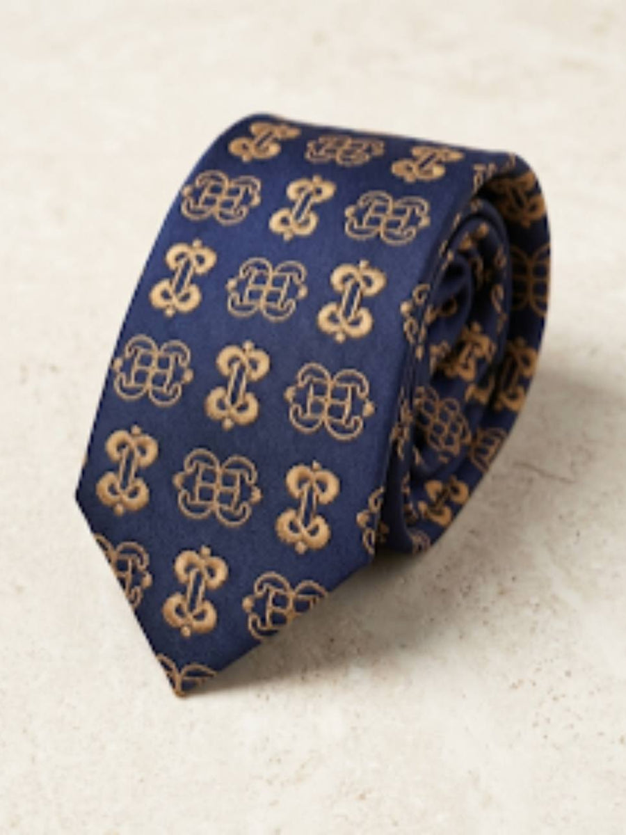 ODEHYE Navy Heritage Tie rolled on warm stone, showing aligned gold Mpatapo and Nyame Biribi Wo Soro symbols