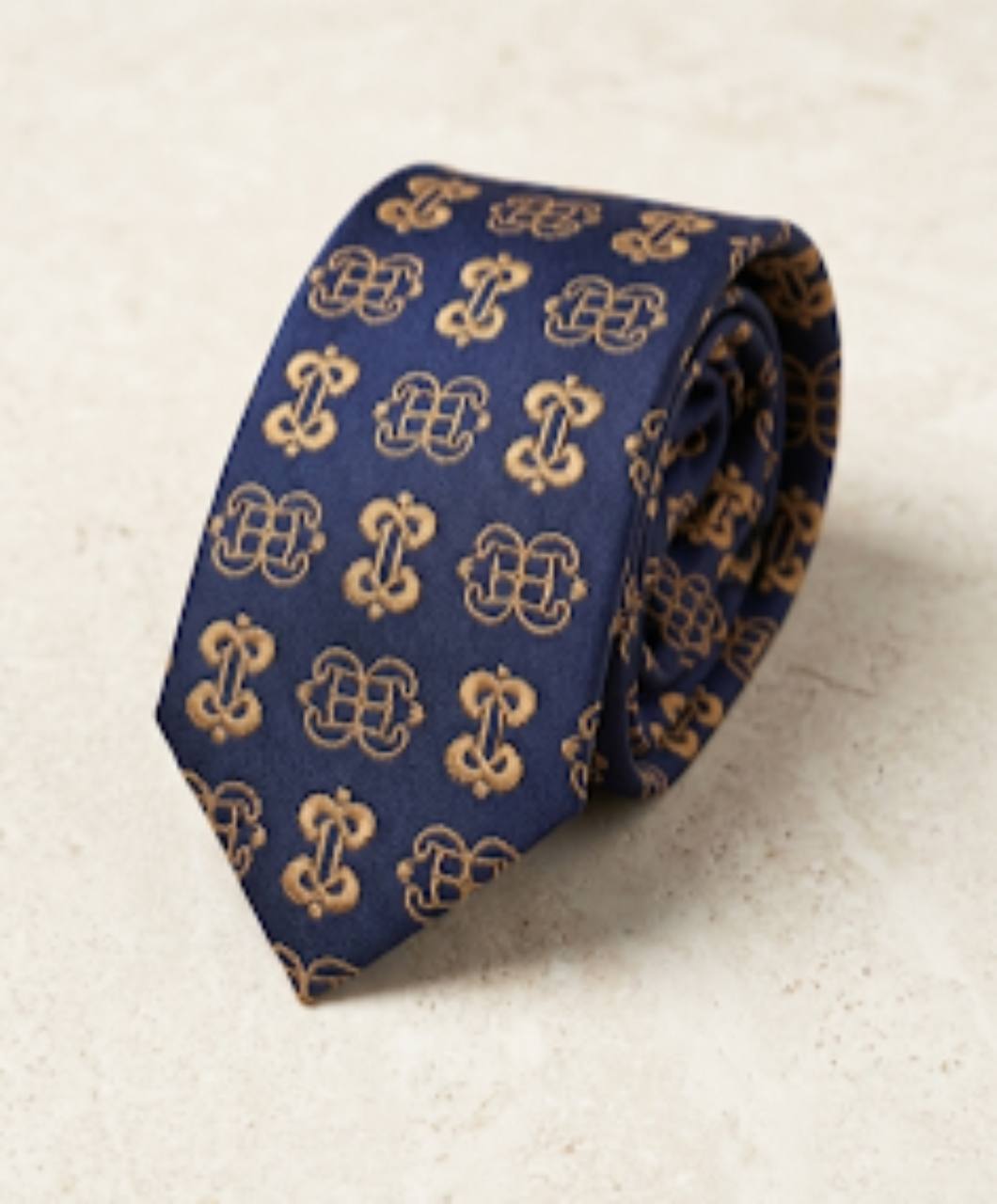 ODEHYE Navy Heritage Tie rolled on warm stone, showing aligned gold Mpatapo and Nyame Biribi Wo Soro symbols